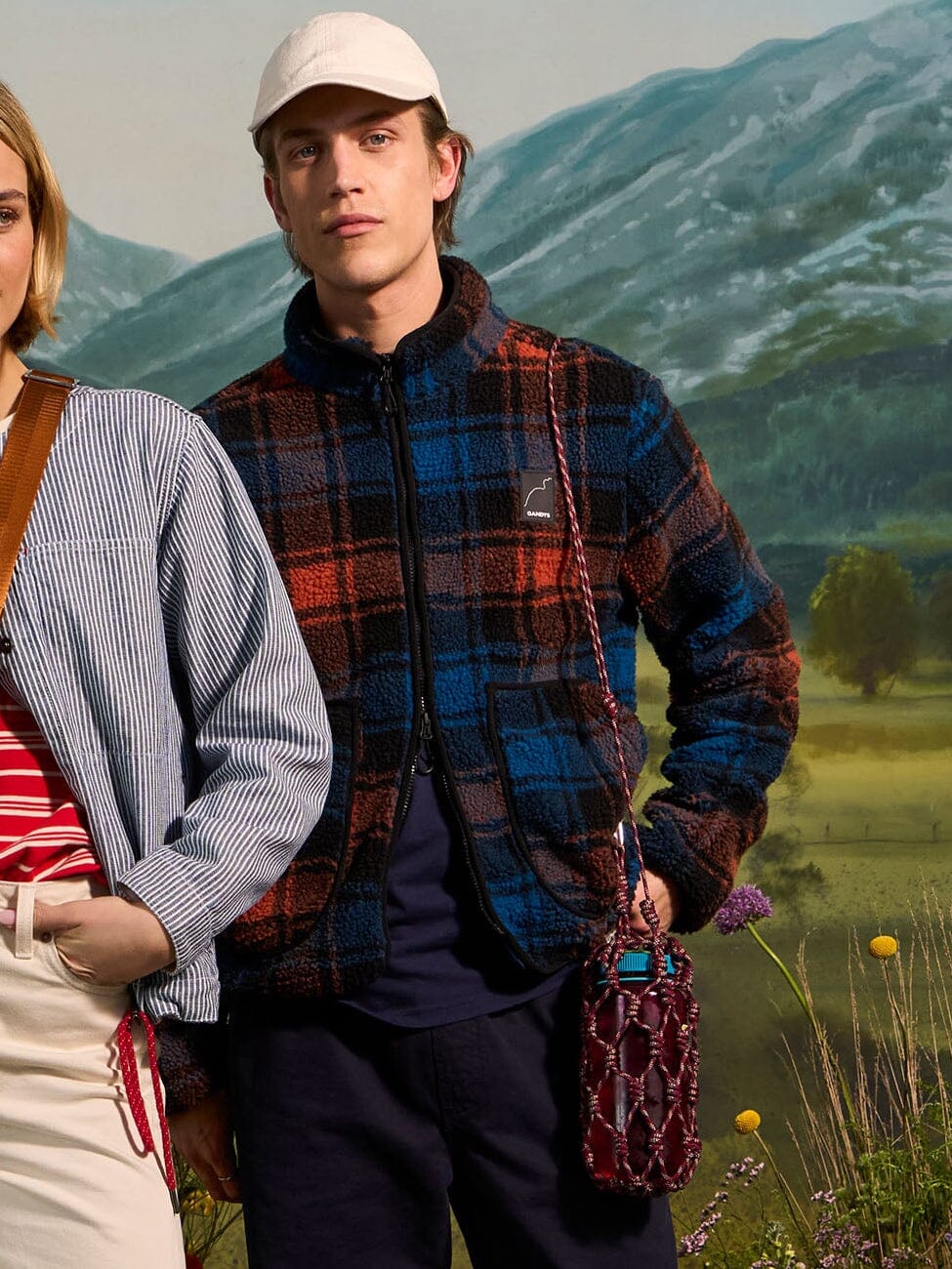 Two people standing in a field with mountains in the background